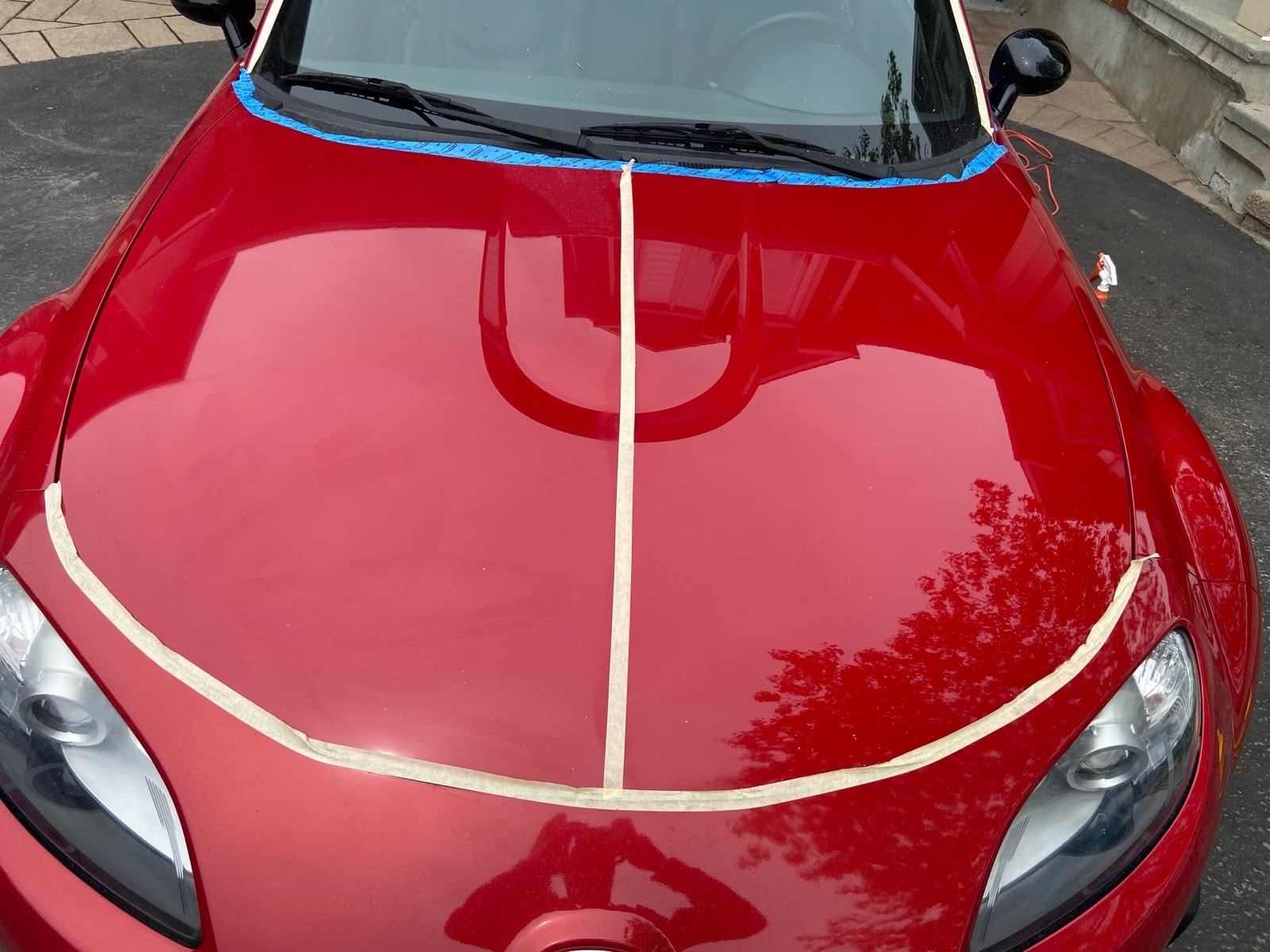 Paint correction and polish on a red Mazda hood — mirror gloss finish